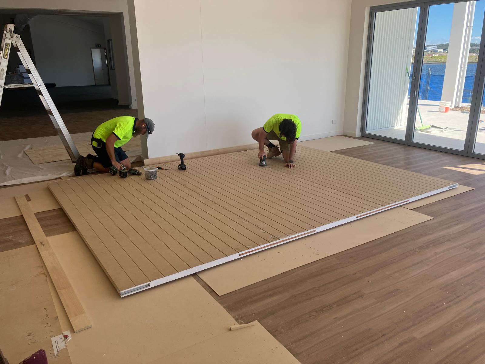 Carpenters installing sliding door track above doorway